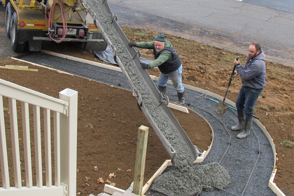 men at work pouring concrete in our new sidewalk